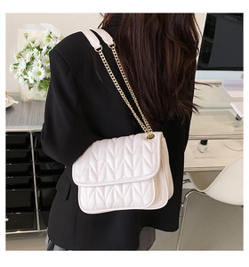 Detailed back view of a white quilted shoulder bag with golden chain and V-shaped texture