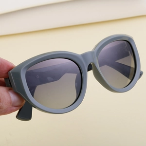 Macro detail of hand-held gray cat-eye sunglasses with gradient lenses and matte finish