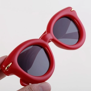 Détail de lunettes de soleil œil-de-chat rouges avec ornements métalliques dorés