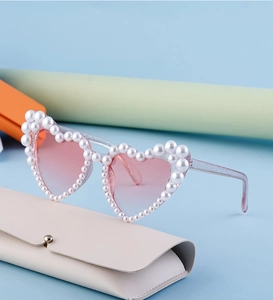 Detail einer Herz-Sonnenbrille mit perlenbesetztem Rahmen und rosa Verlauf Gläsern