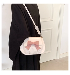 Dettaglio della borsa bianca con fiocco rosa e tracolla intrecciata sulla spalla