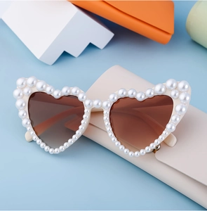 Detail der herzförmigen Sonnenbrille mit perlenbesetztem Rahmen und getönten Gläsern