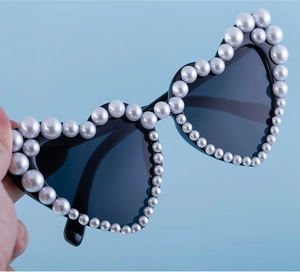 Detailansicht der herzförmigen Sonnenbrille mit elegantem Perlenbesatz auf schwarzem Rahmen