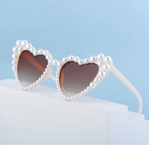 Detail der herzförmigen Sonnenbrille mit perlenbesetztem cremefarbenem Rahmen und Gläsern