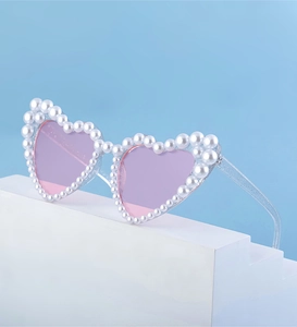 Detail einer herzförmigen Sonnenbrille mit rosa Gläsern und Perlenbesatz am Rahmen