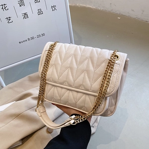 Quilted off-white chain bag with zigzag patterns and gold hardware in hand