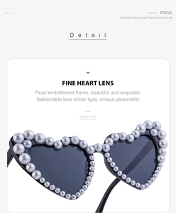Detail einer herzförmigen Sonnenbrille mit weißem Perlenrahmen und dunklen Gläsern