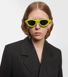 Front close-up of fluorescent green Y2K sunglasses with dark lenses on a fashion model