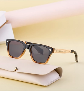 Détail de lunettes de soleil vintage carrées avec branches dorées sur étui beige
