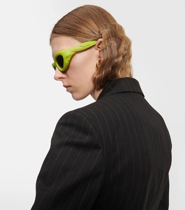 Detail of neon green Y2K wraparound sunglasses with thick sculptural frames on a model