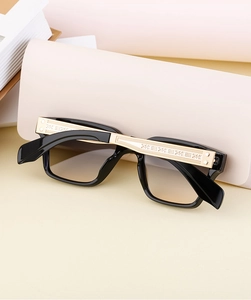 Détail de lunettes de soleil carrées avec branches gravées dorées et verres dégradés bruns