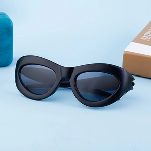 Detail of matte black cat eye sunglasses with blue lenses and futuristic wide temples