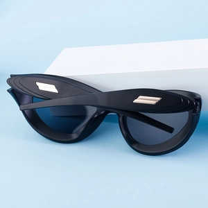 Detail of matte black cat-eye sunglasses with signature golden parallel metal bars