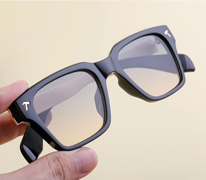 Gros plan de lunettes de soleil carrées noires avec verres dégradés et accents T
