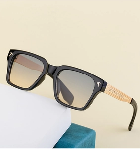 Détail de lunettes de soleil carrées avec branches dorées et verres dégradés marron
