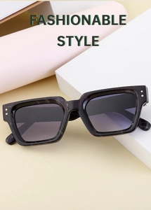 Detail of square black textured sunglasses frame with metallic rivets on a geometric prop