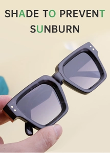 Close-up of black square sunglasses featuring gold metal hinge detail and side accents