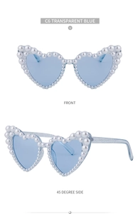 Detail einer herzförmigen Sonnenbrille mit blauen Gläsern und Rahmen mit Perlenverzierung