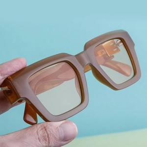 Gros plan de lunettes de soleil carrées kaki avec des verres teintés jaune clair