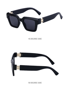 Détail de lunettes de soleil carrées noires avec charnière en métal doré et branches larges