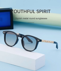 Close-up of black square sunglasses with gold temples and diamond-pattern embossing