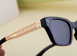 Detail of gold metal temples with geometric engraving and star rivets on black sunglasses