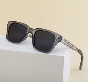 Detail of square translucent grey sunglasses frame with metal arrow rivets and textured core