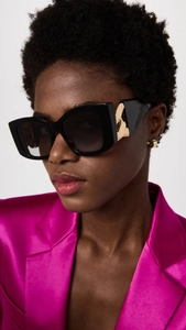 Close-up of cat-eye sunglasses with luxury gold chain temples on a fashion model