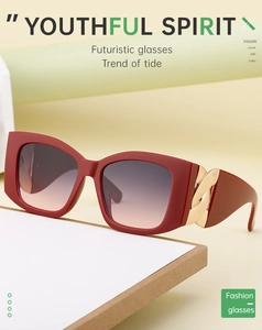 Detail view of red oversized cat-eye sunglasses with gold chain link temple accent