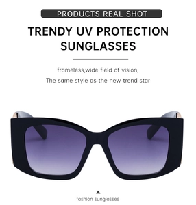 Detail of chunky black frame sunglasses with purple gradient lenses and gold accents