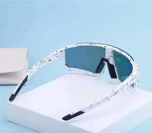 Detailed view of sports sunglasses with white speckled frame and blue gradient shield lens