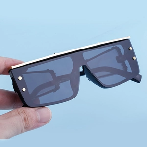 Detail of square frame sunglasses with gold metal bar and decorative rivets on lenses