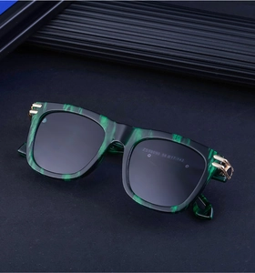 Detail of square sunglasses with green marble pattern frames and golden metal hinges