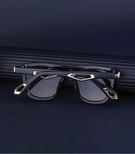 Detail of square black sunglasses with gold geometric hollow metal hinge design