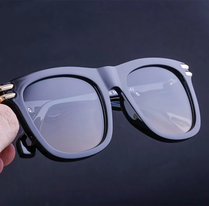 Detailed close-up of square black sunglasses featuring gold accents and gradient lenses