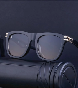 Close-up of matte black square frame sunglasses with gold hinge detail and gradient lenses