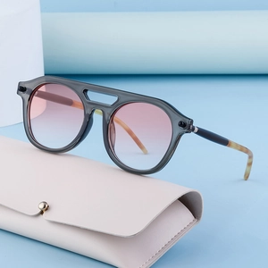 Steampunk sunglasses with grey frames and pink gradient lenses on a leather case