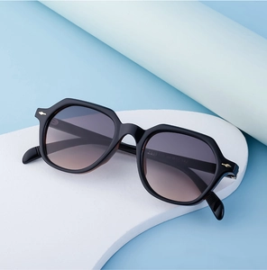 Detail view of square sunglasses with gold accents and gradient lenses on a display stand