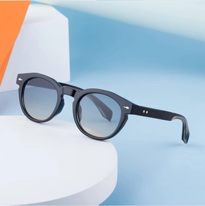 Detail of black oval sunglasses with blue gradient lenses and silver arrow studs