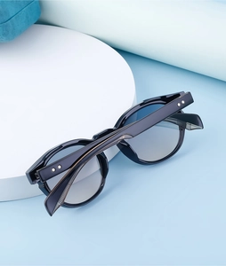 Detail view of oval black sunglasses featuring metal star rivets on the temples