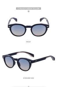 Detail view of oval black sunglasses with gradient lenses and gold metal arrow accents