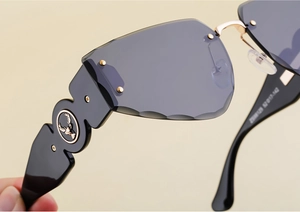 Detail of wide temple featuring a golden deer emblem on rimless sunglasses