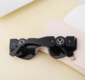 Detail of wide geometric temples with golden stag emblem on rimless sunglasses