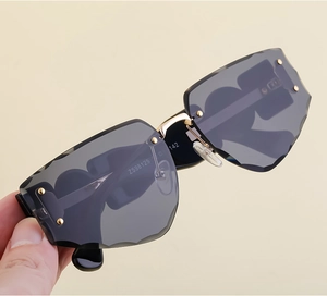 Close-up of frameless sunglasses with wave-cut edges and gold hinge details
