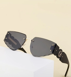 Close-up of frameless sunglasses with wave cut gray lenses and wide black temples