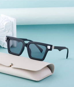 Detail of square vintage sunglasses with black matte frames and blue lenses on a leather case