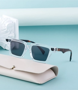 Detail view of square frame sunglasses with tortoiseshell temples on a beige leather case