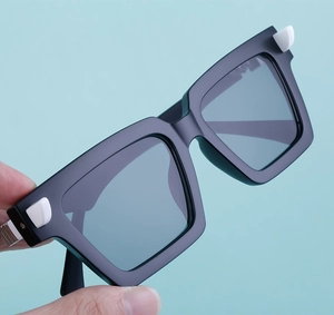 Detail of square black sunglasses with white geometric accents and dark gray lenses