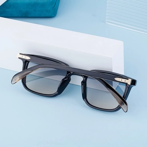 Close-up of square black sunglasses with gradient lenses and gold metal temple accents