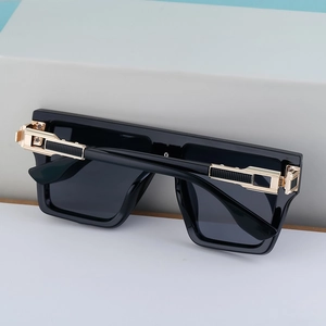 Gros plan de lunettes de soleil carrées noir brillant avec détail doré sur la branche